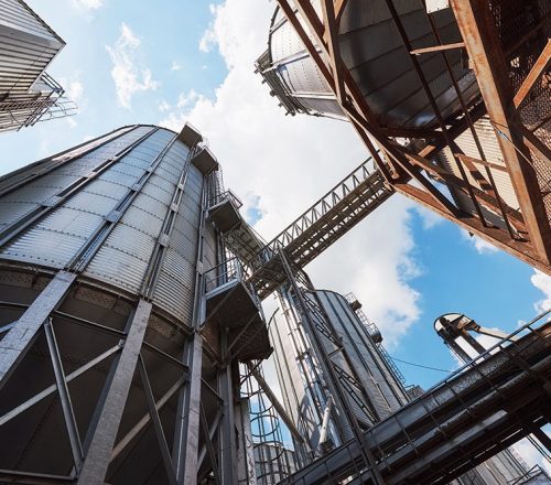 Agricultural Silos. Building Exterior. Storage and drying of grains, wheat, corn, soy, sunflower against the blue sky with white clouds.